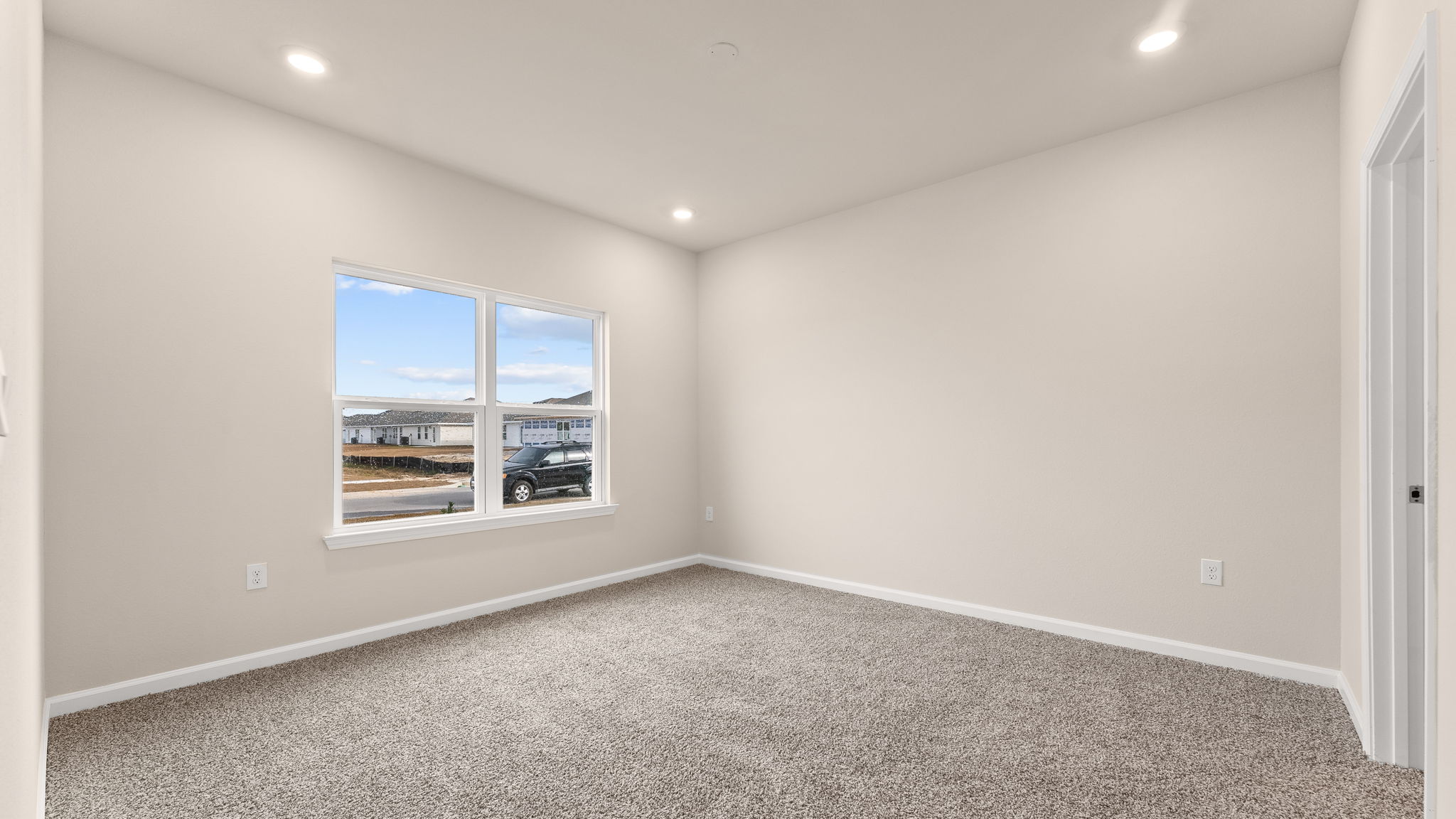 Primary bedroom with carpet flooring and windows.