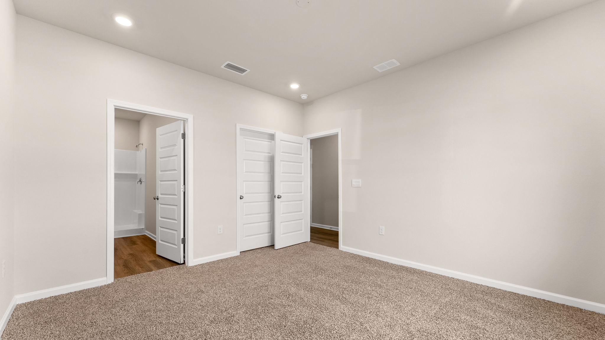 Primary bedroom with carpet floors and bathroom entrance.