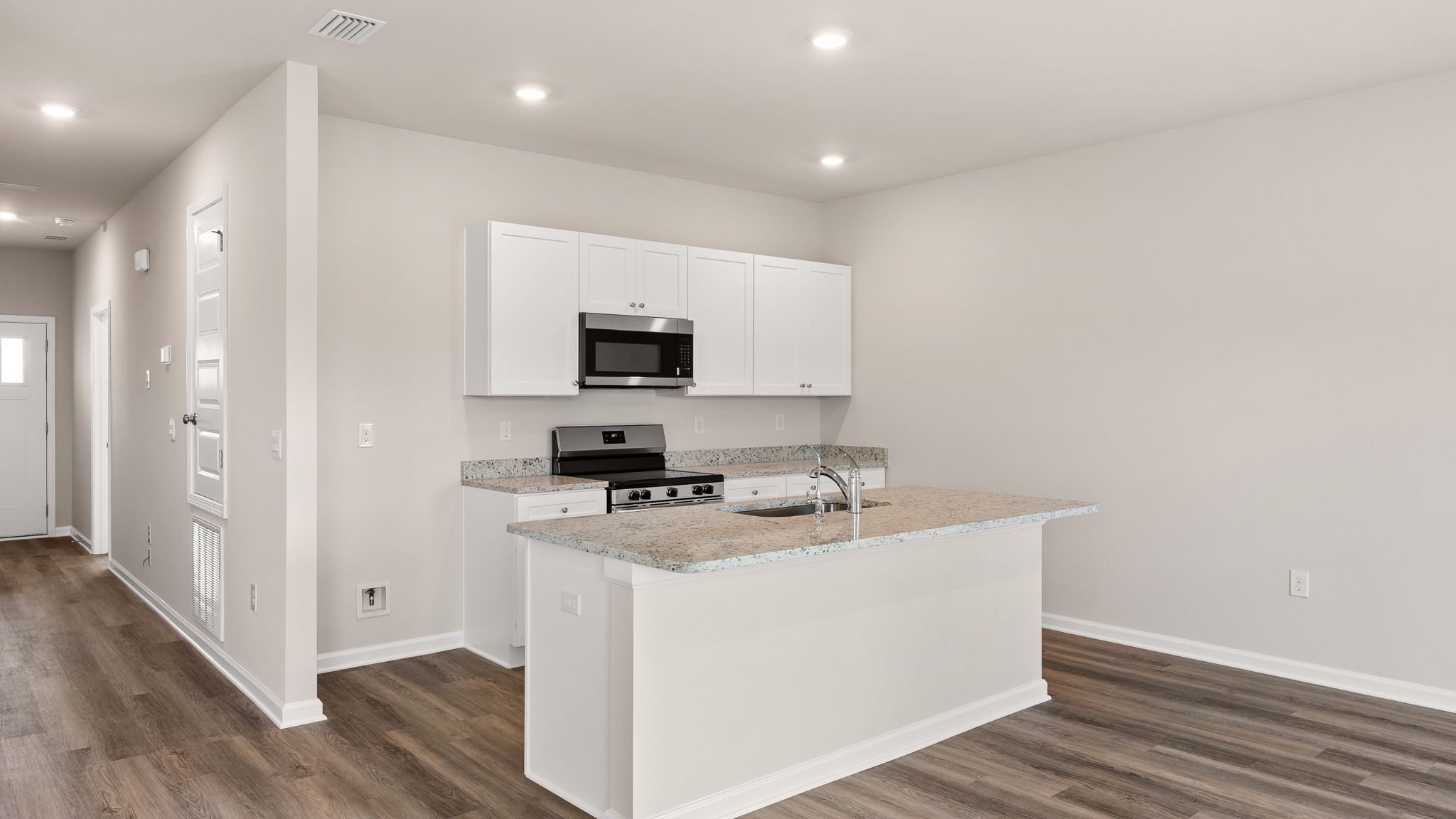 Kitchen with island and granite countertops with white cabinets and stainless-steel appliances.