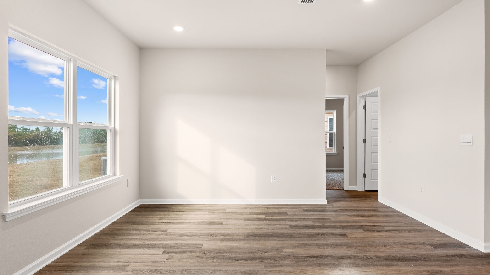 Living room with EVP flooring and windows next to bedrooms.