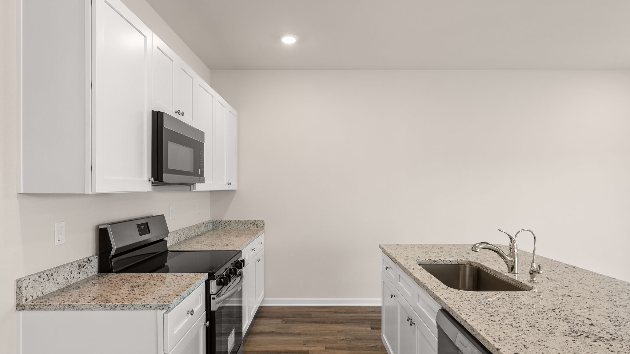 Kitchen with island and granite countertops with white cabinets and stainless-steel appliances.