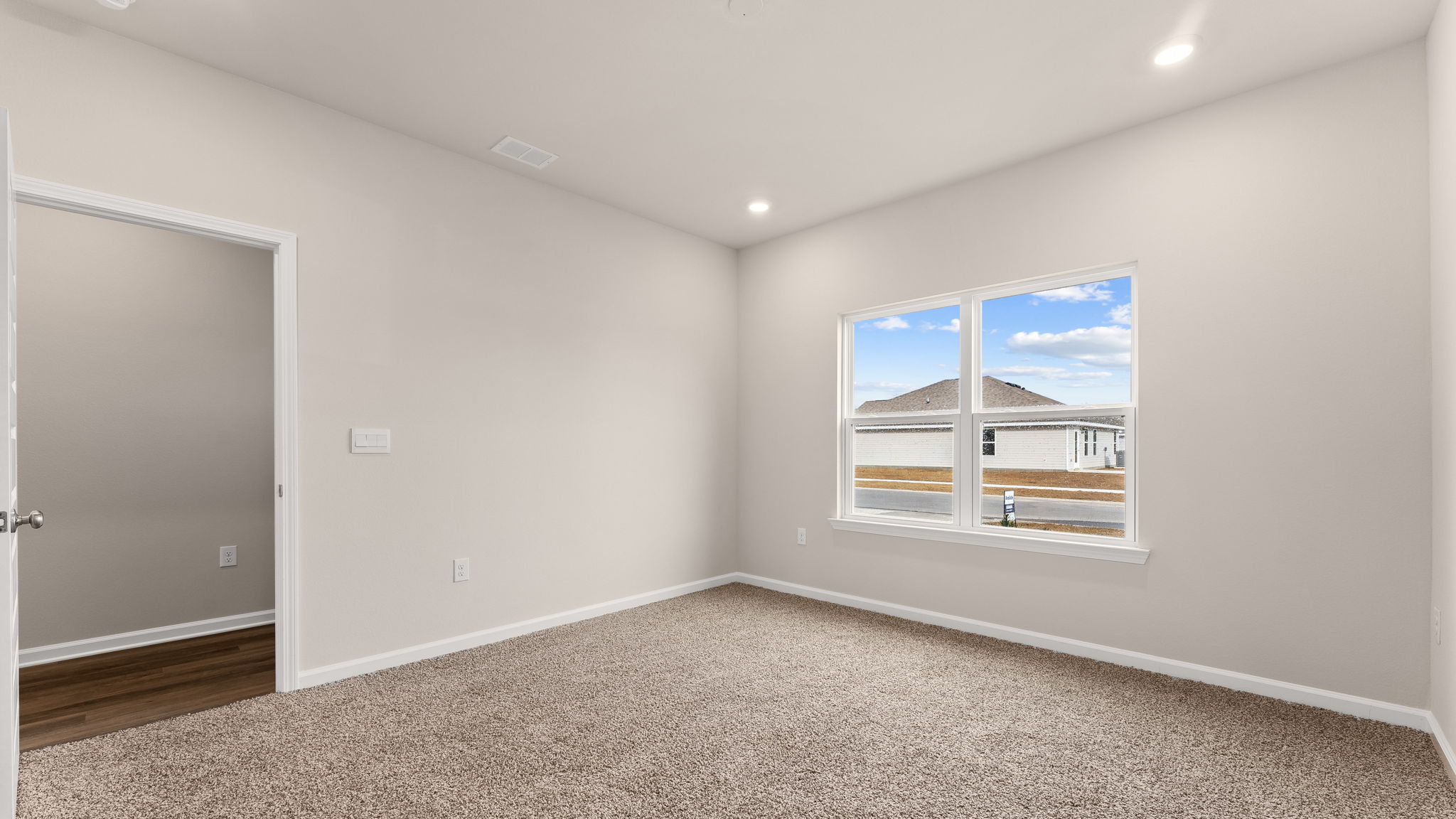Primary bedroom with carpet flooring and windows.