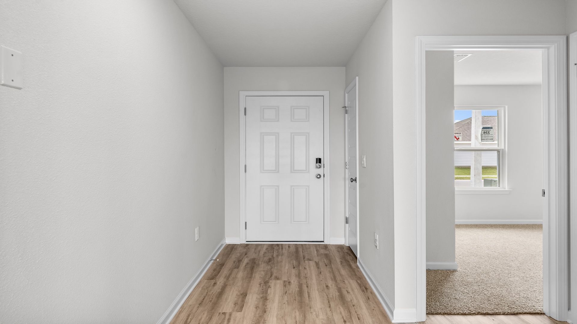 Front entrance next to bedroom with front door and EVP flooring.