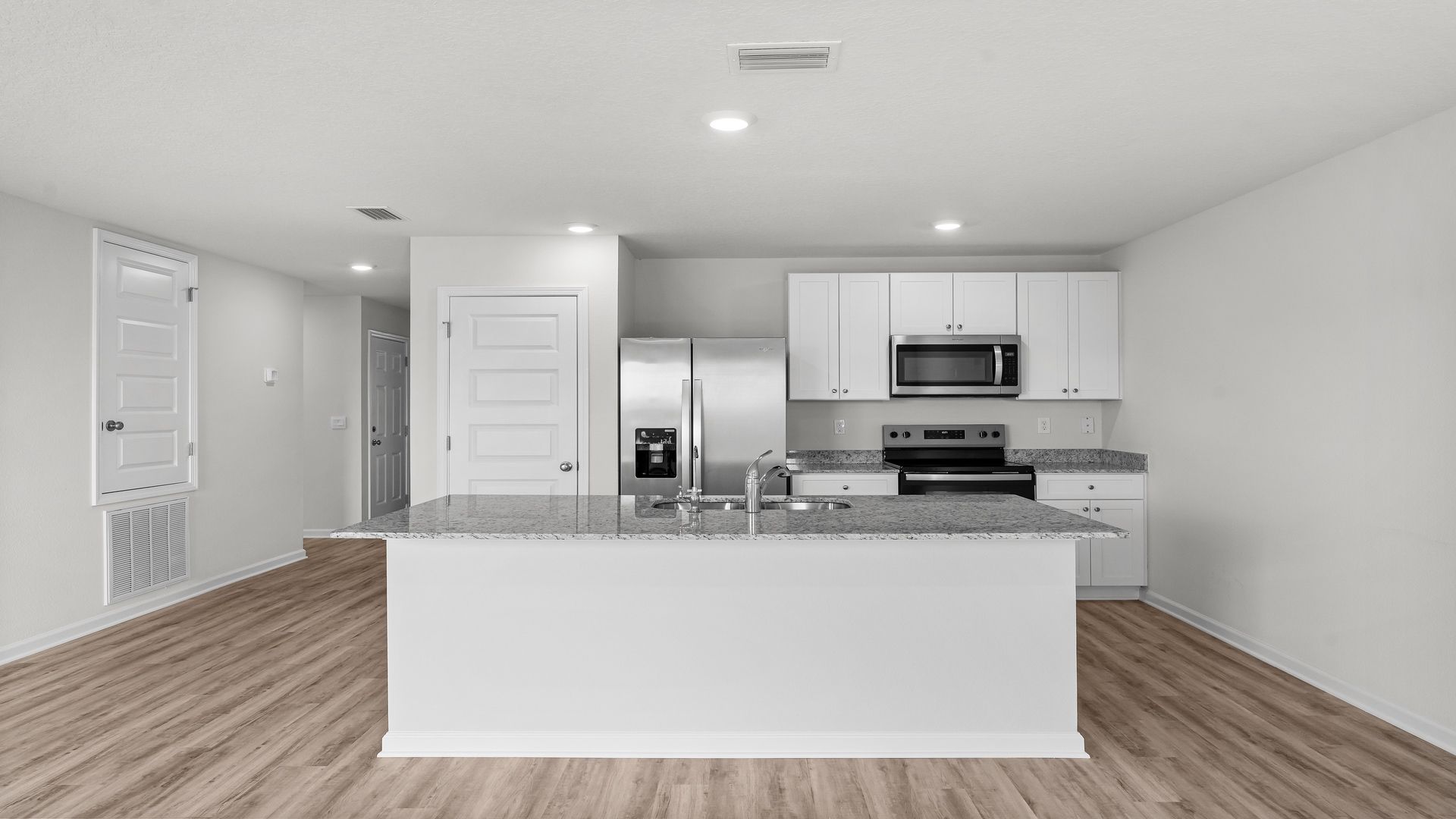 Kitchen island with granite countertops and stainless-steel appliances and pantry.