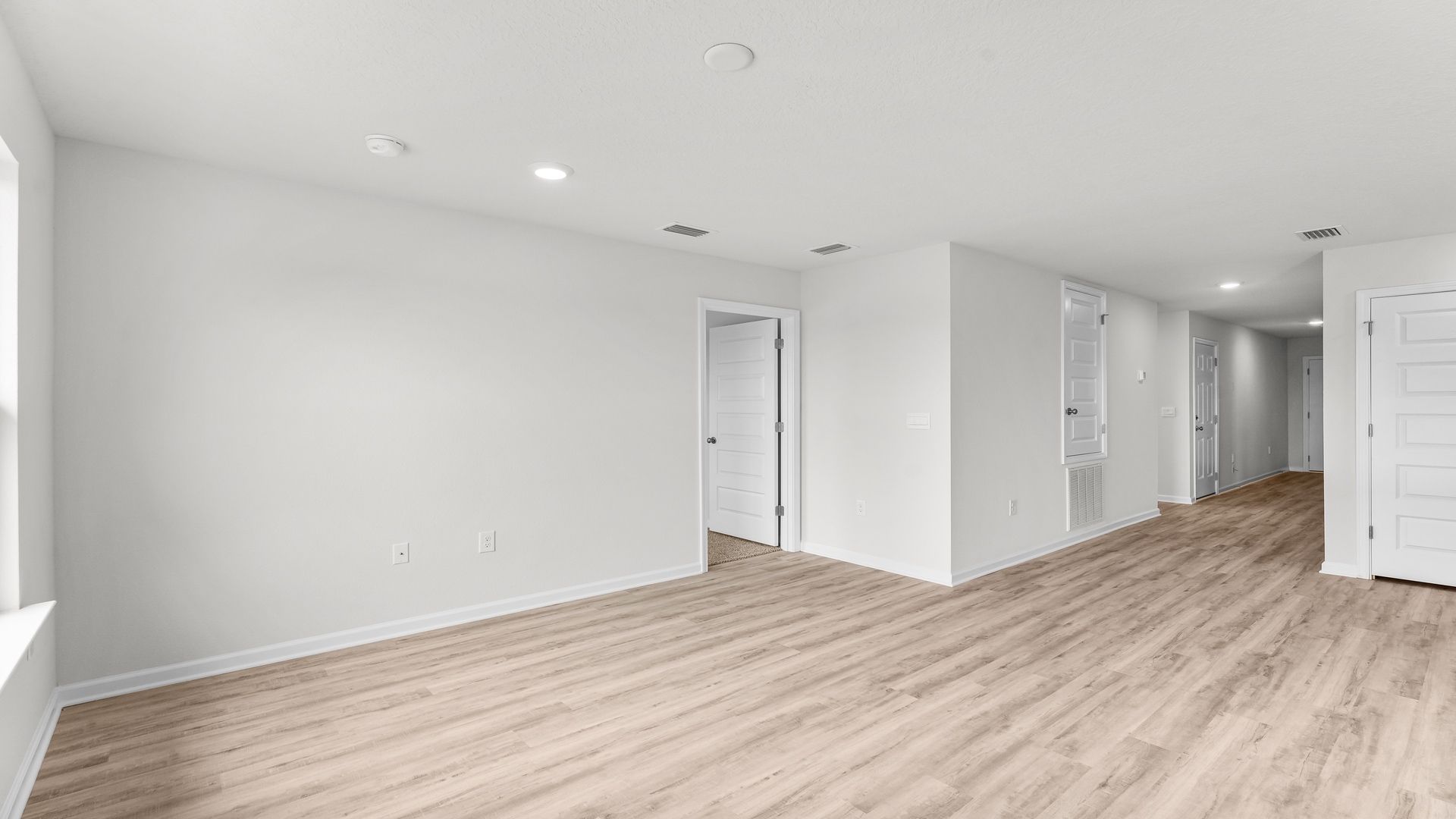 Open living room with EVP flooring and bedroom door.