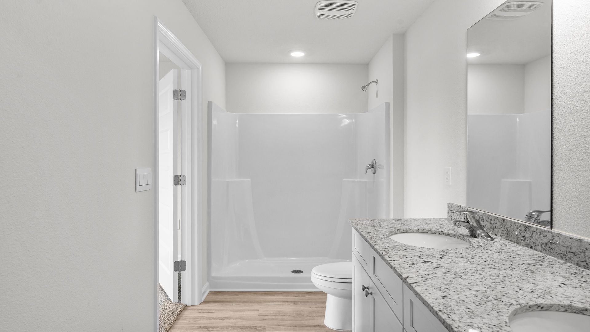 Primary bathroom with double vanity and granite countertops and toilet and shower.