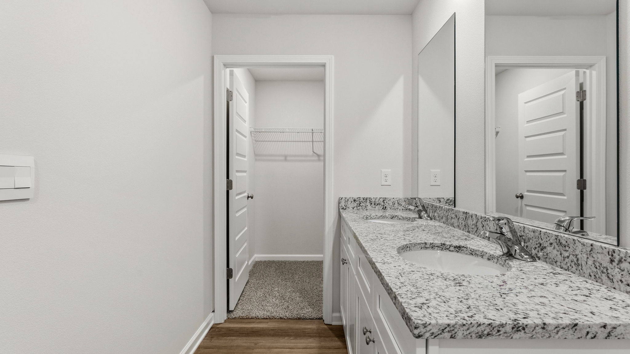 Primary bathroom with double vanity and granite countertops and walk-in closet.