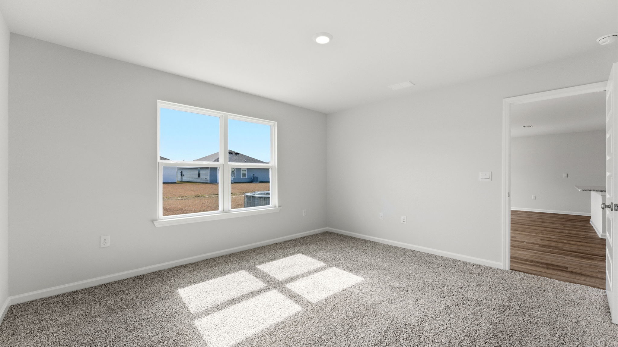 Primary bedroom with carpet flooring and two windows and living room entrance.
