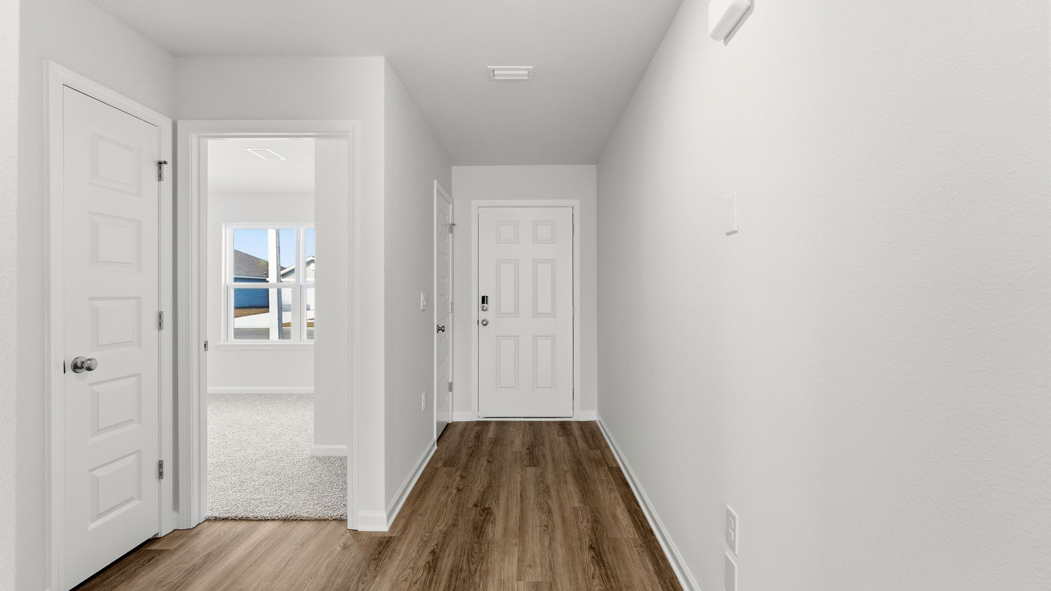 Front entrance next to bedroom with front door and EVP flooring.