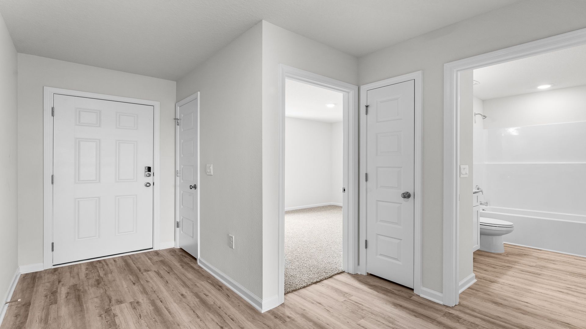 Front entrance next to bedroom with front door and EVP flooring.