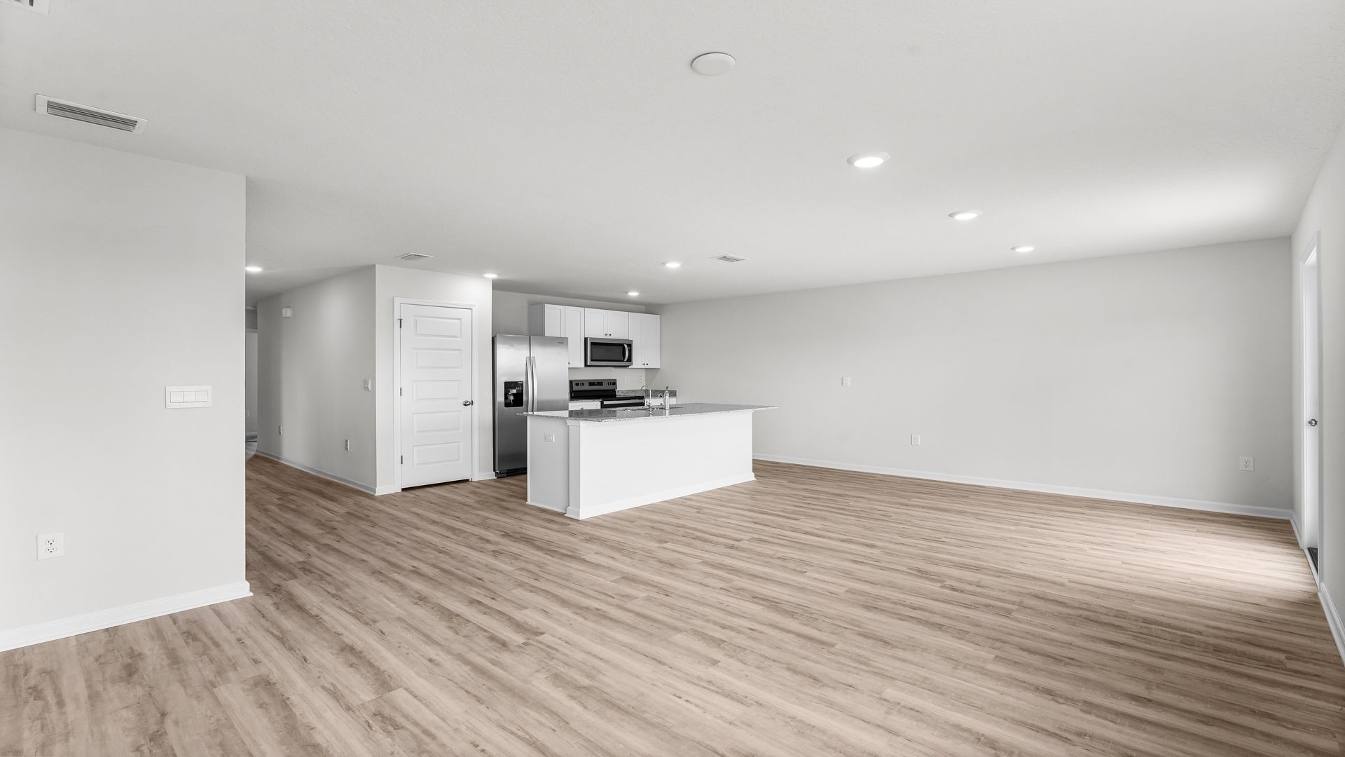 Open living room with EVP flooring and kitchen and dining room.