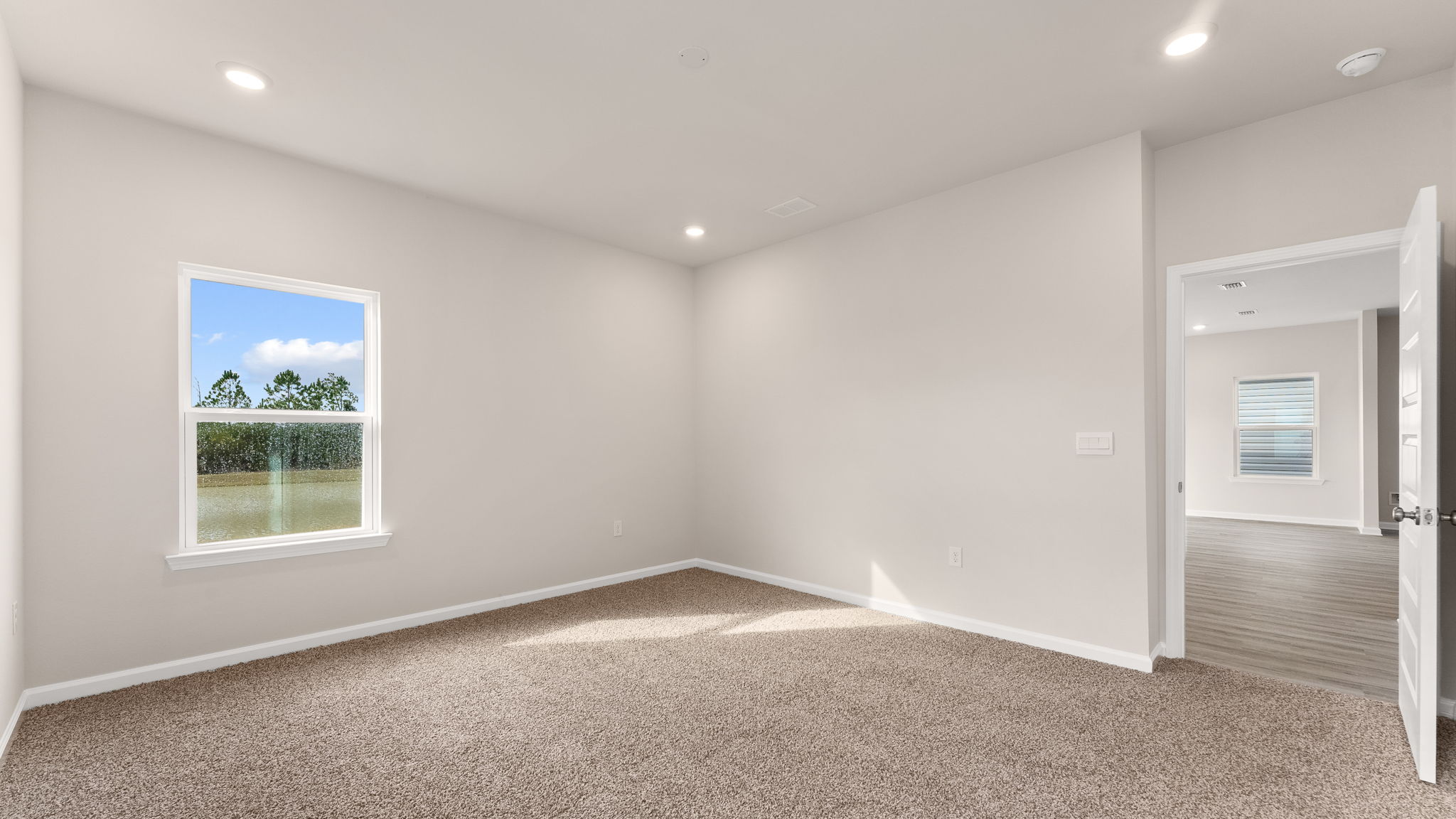 Primary bedroom with carpet floors and living room entrance.