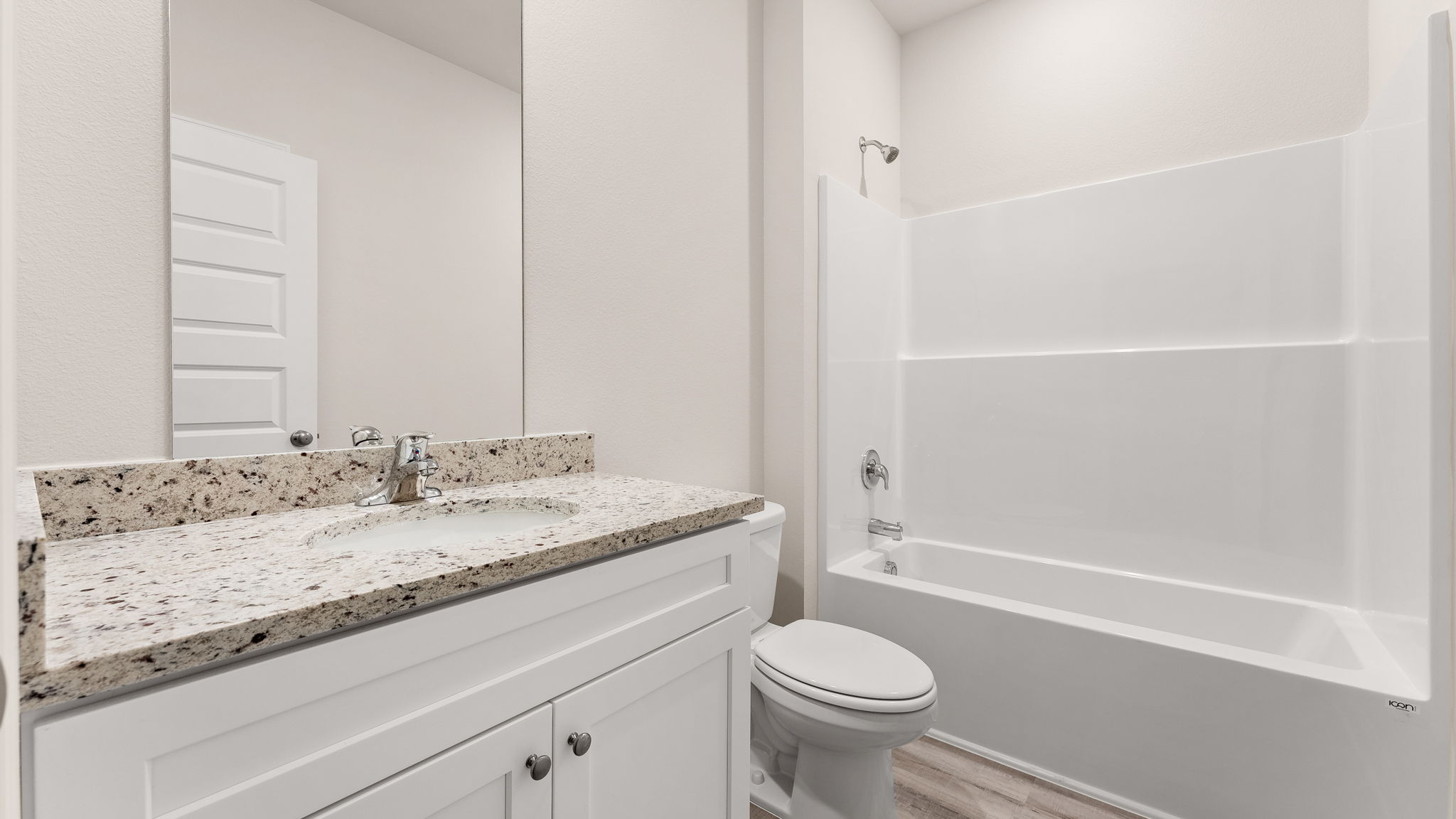 Bathroom with single vanity sink and granite countertops with white cabinets and EVP flooring and shower and toilet.