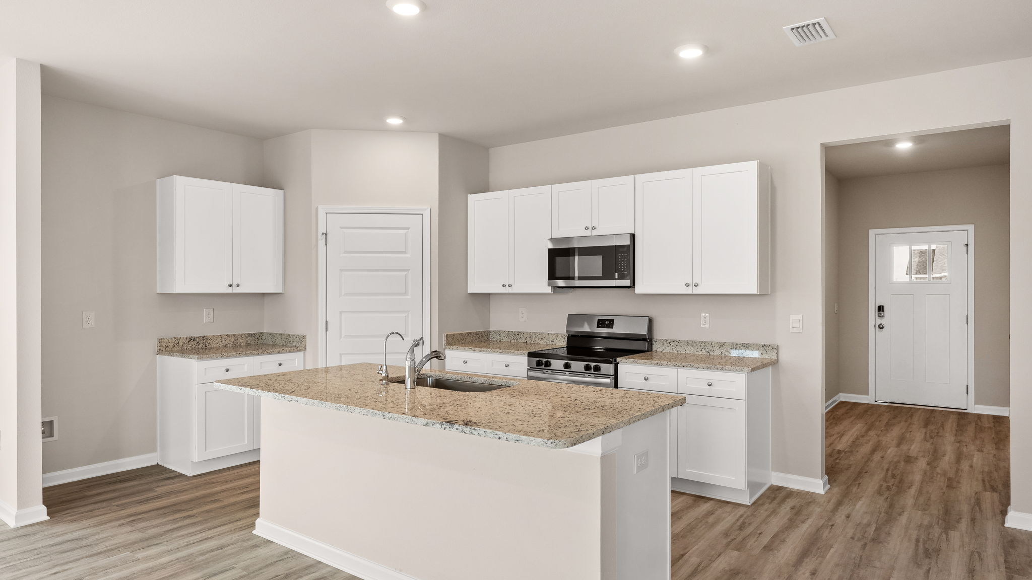 Kitchen with island and granite countertops with white cabinets and stainless-steel appliances.