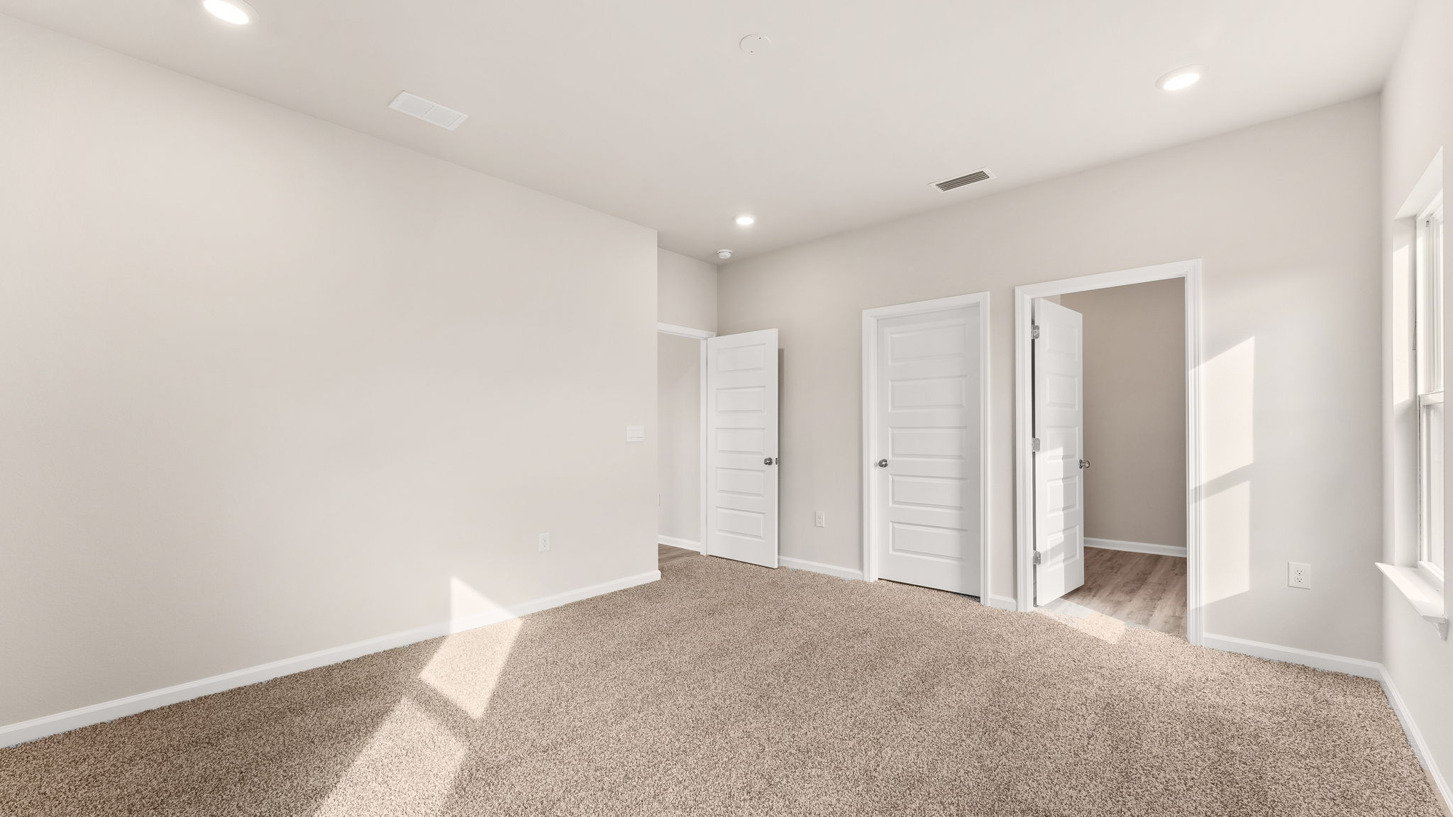 Primary bedroom with carpet floors and bathroom entrance.