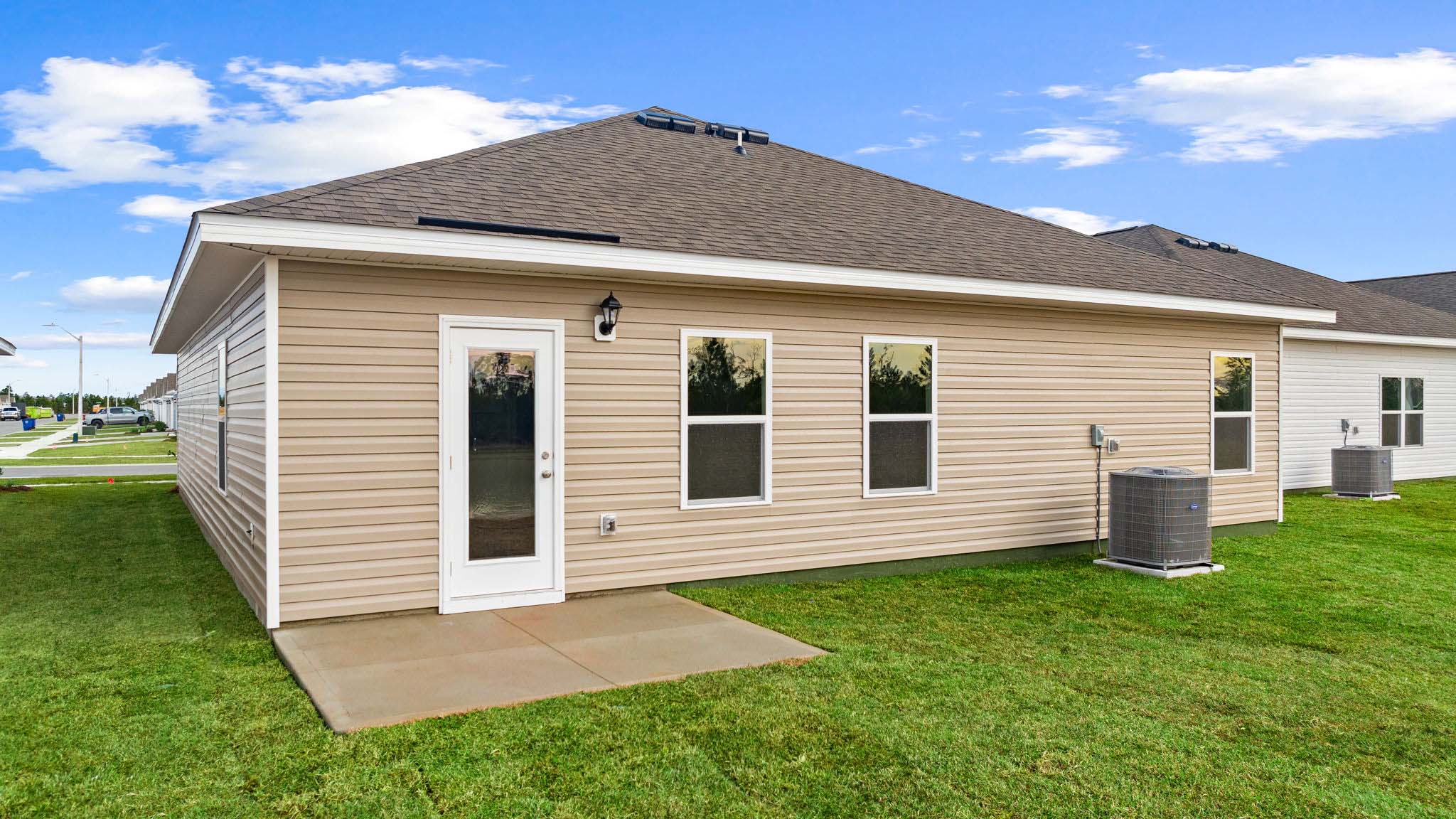 Walker plan rear of home with concrete pad and back yard.