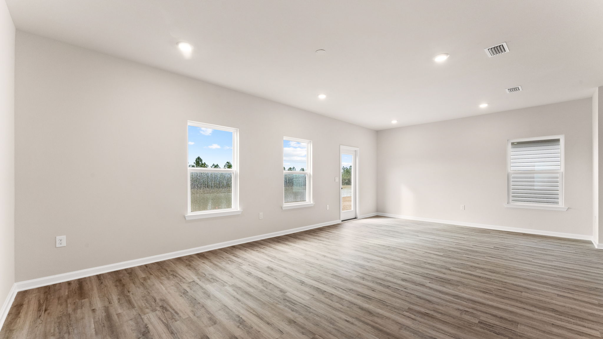 Living room with EVP flooring and dinging area and back door and windows.