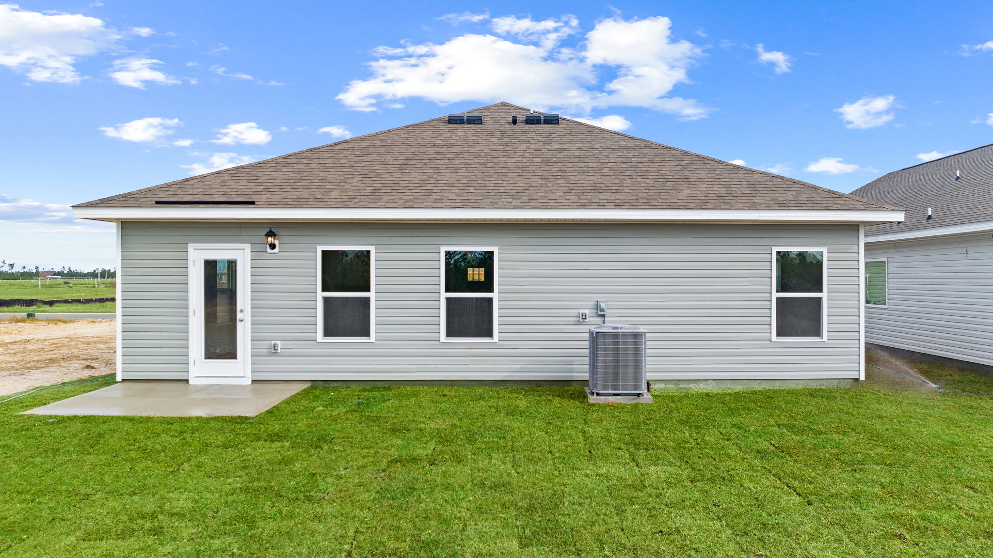 Walker plan rear of home with concrete pad and back yard.