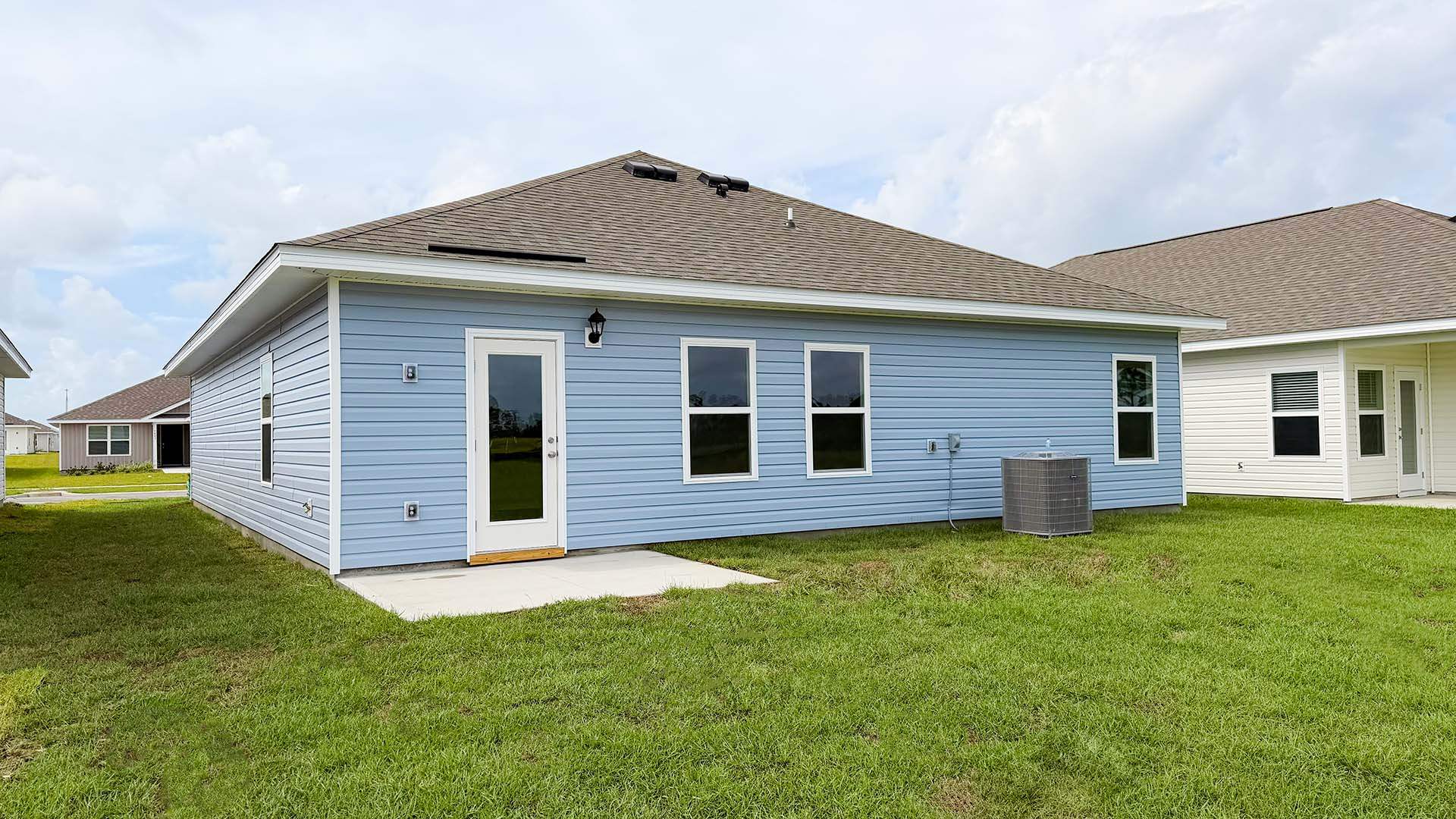 Walker plan rear of home with concrete pad and back yard.
