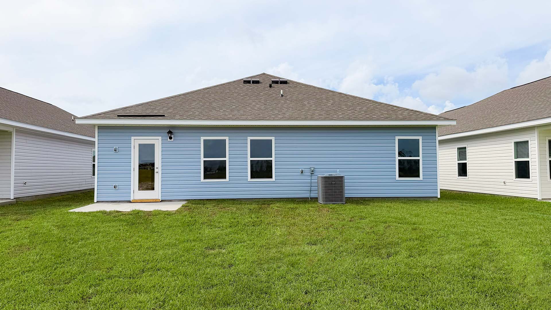Walker plan rear of home with concrete pad and back yard.