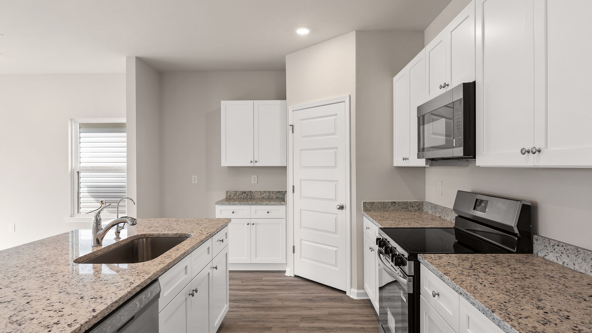 Kitchen with island and granite countertops with white cabinets and stainless-steel appliances.