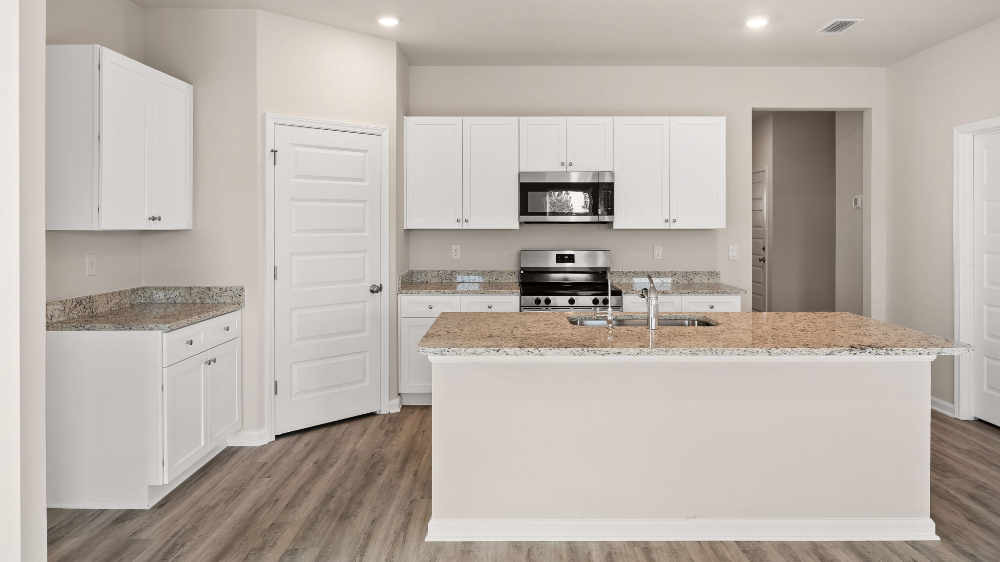 Kitchen with island and granite countertops with white cabinets and stainless-steel appliances.