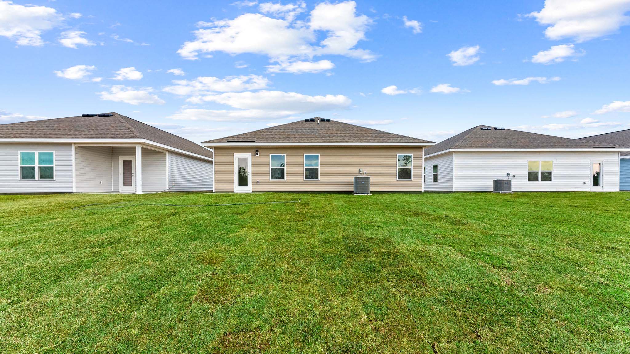 Walker plan rear of home with concrete pad and back yard.