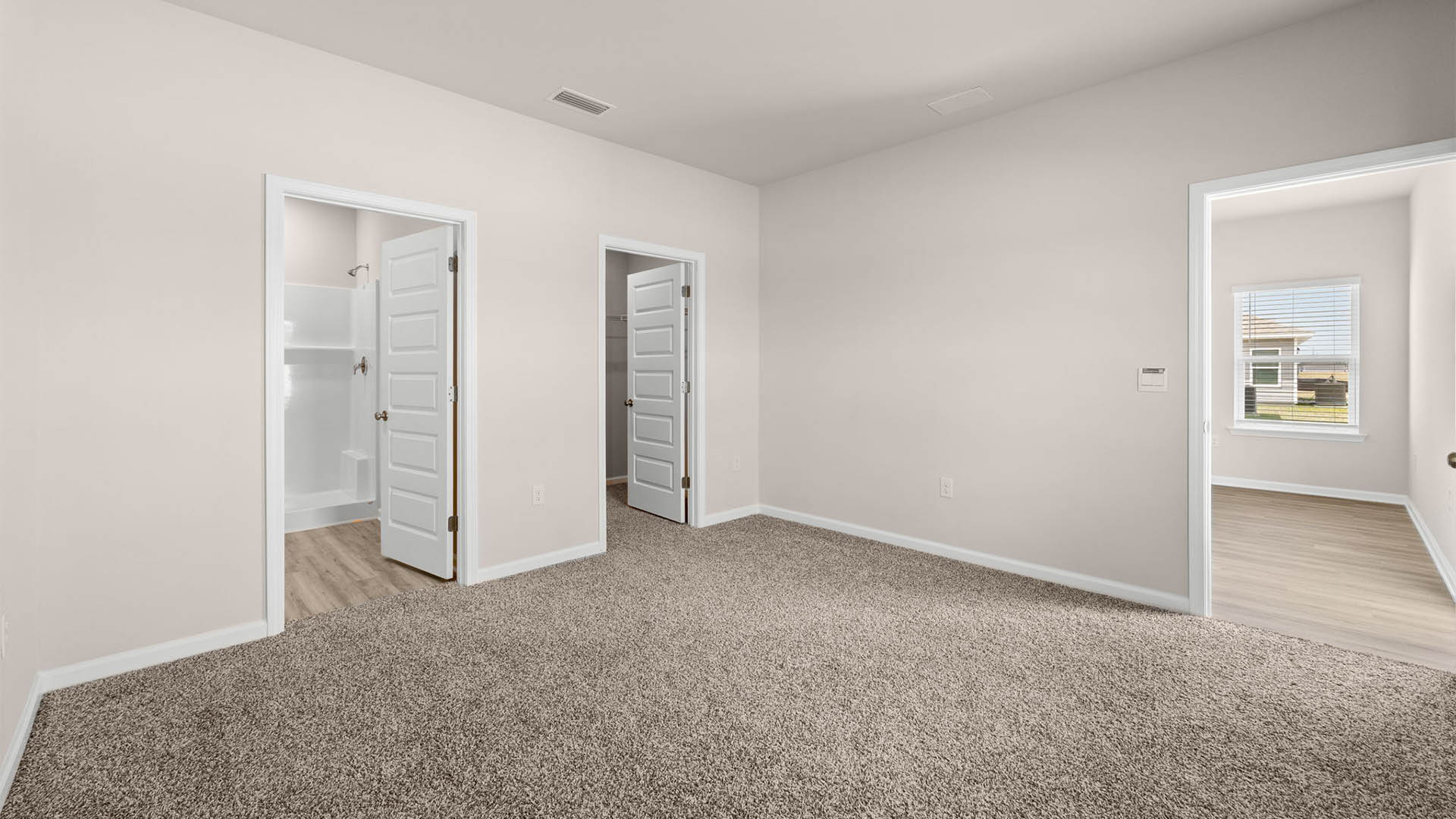 Primary bedroom with carpet floors and closet and bathroom entrance.
