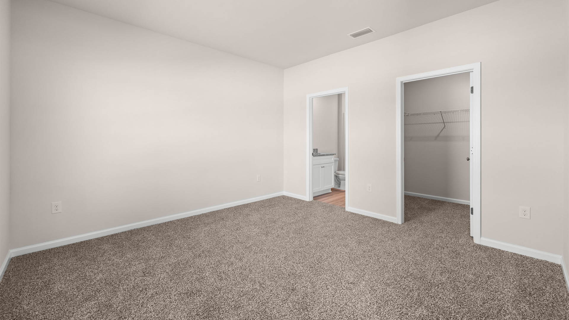 Primary bedroom with carpet floors and closet and bathroom entrance.