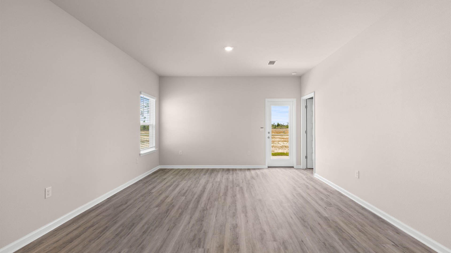 Open living room with EVP flooring and back door and bedroom entrance.