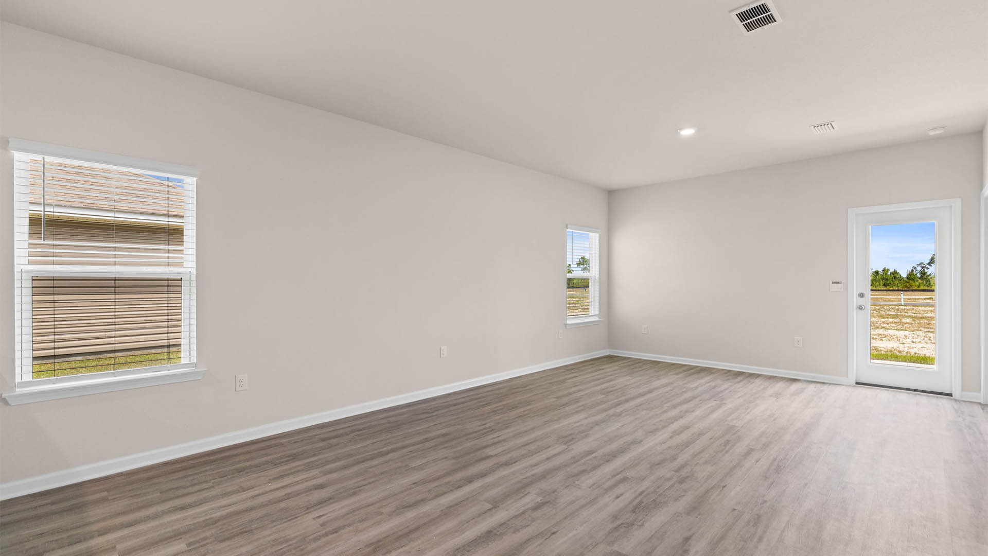 Open living room with EVP flooring and back door and windows.