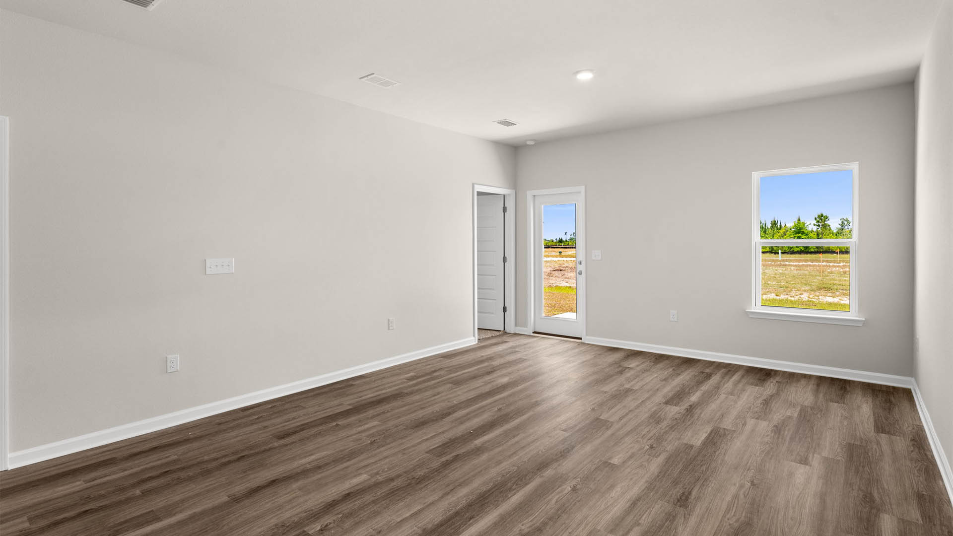 Open living room with EVP flooring and back door and windows.