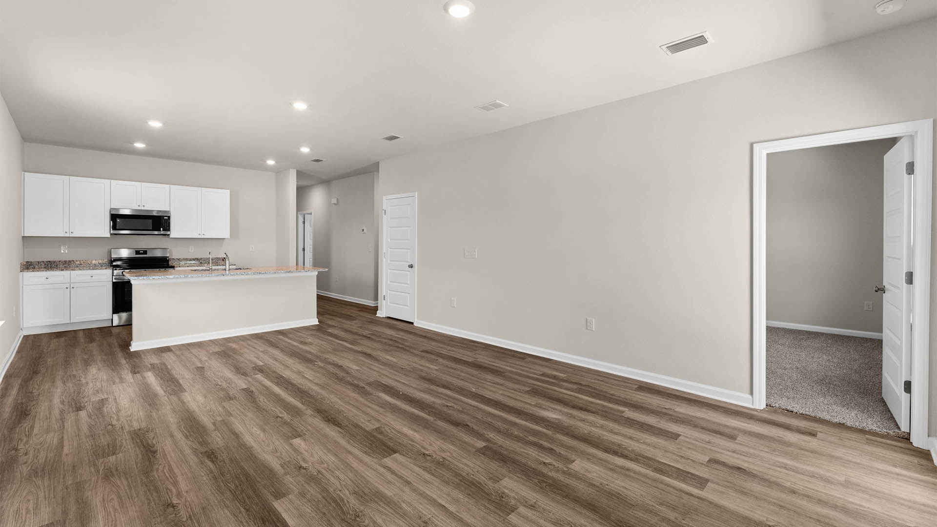 Open living room with EVP flooring and back door and bedroom entrance.