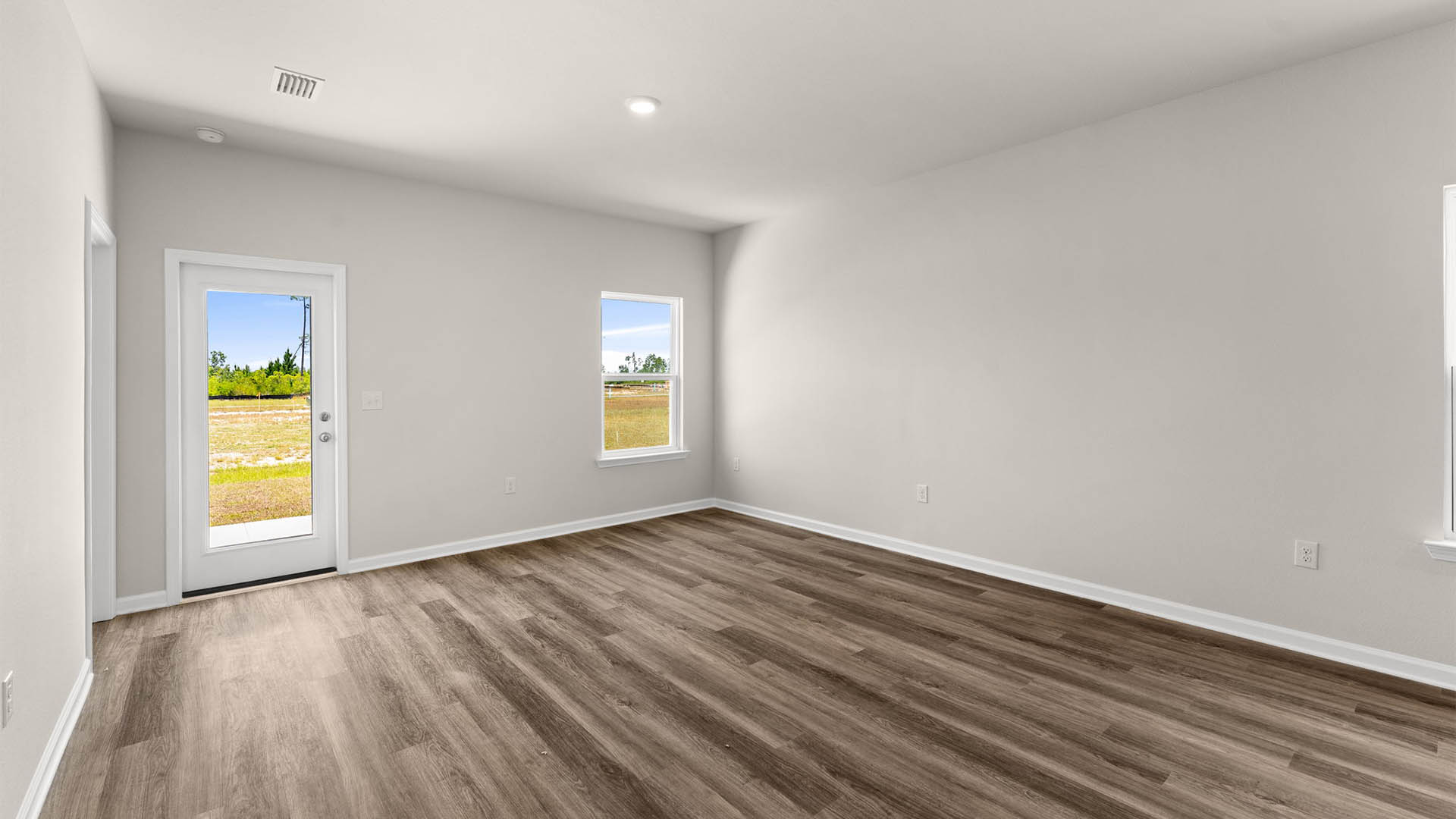 Open living room with EVP flooring and back door and windows.