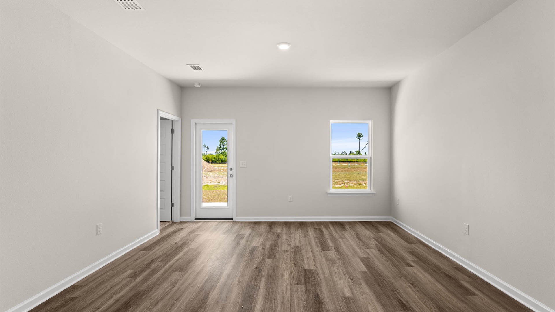 Open living room with EVP flooring and back door and windows.
