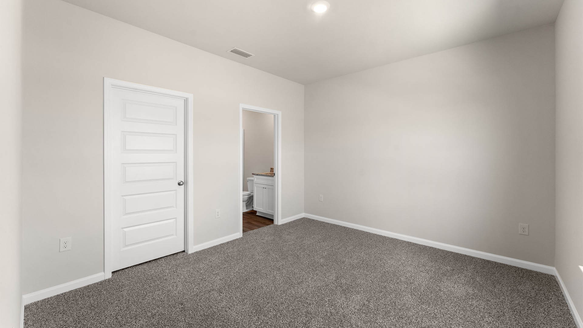 Primary bedroom with carpet floors and closet and bathroom entrance.