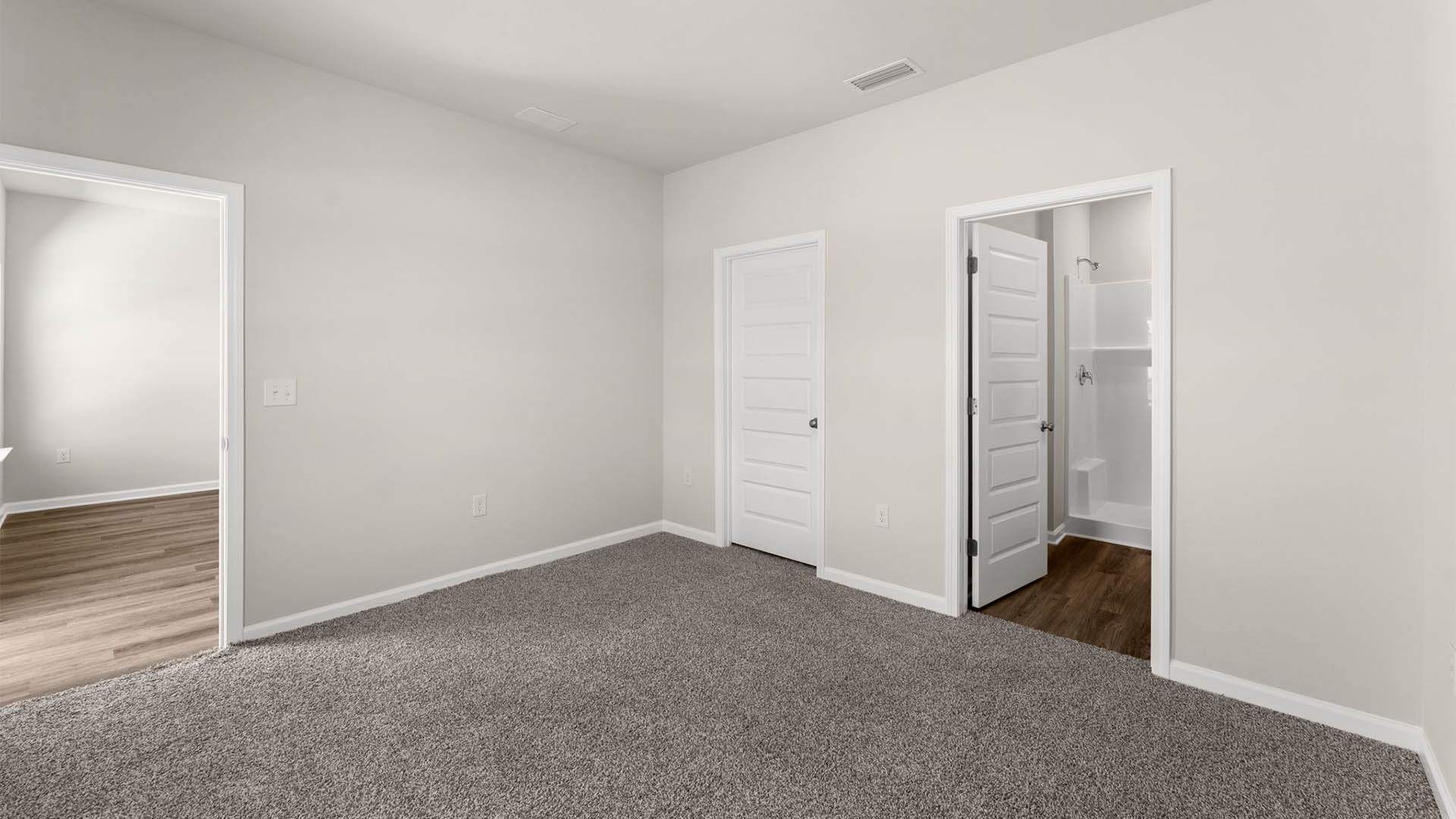 Primary bedroom with carpet floors and closet and bathroom entrance.