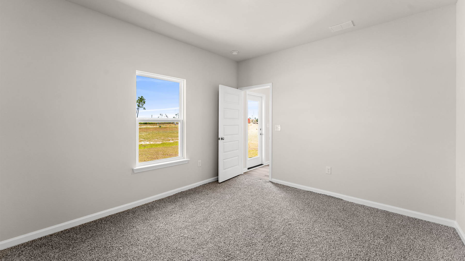 Primary bedroom with carpet floors and living room entrance and window.