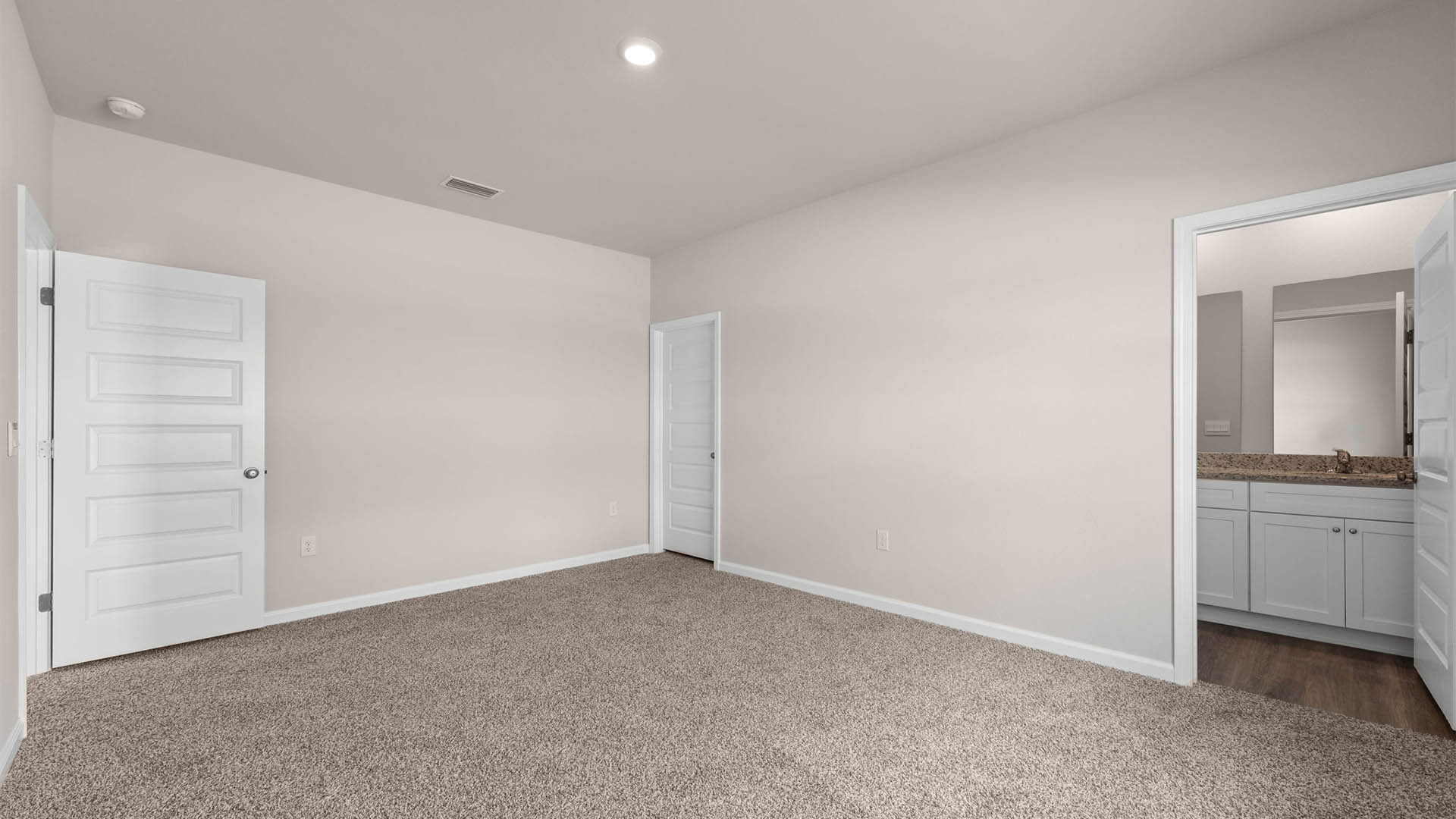 Primary bedroom with carpet floor and closet and bathroom entrance.