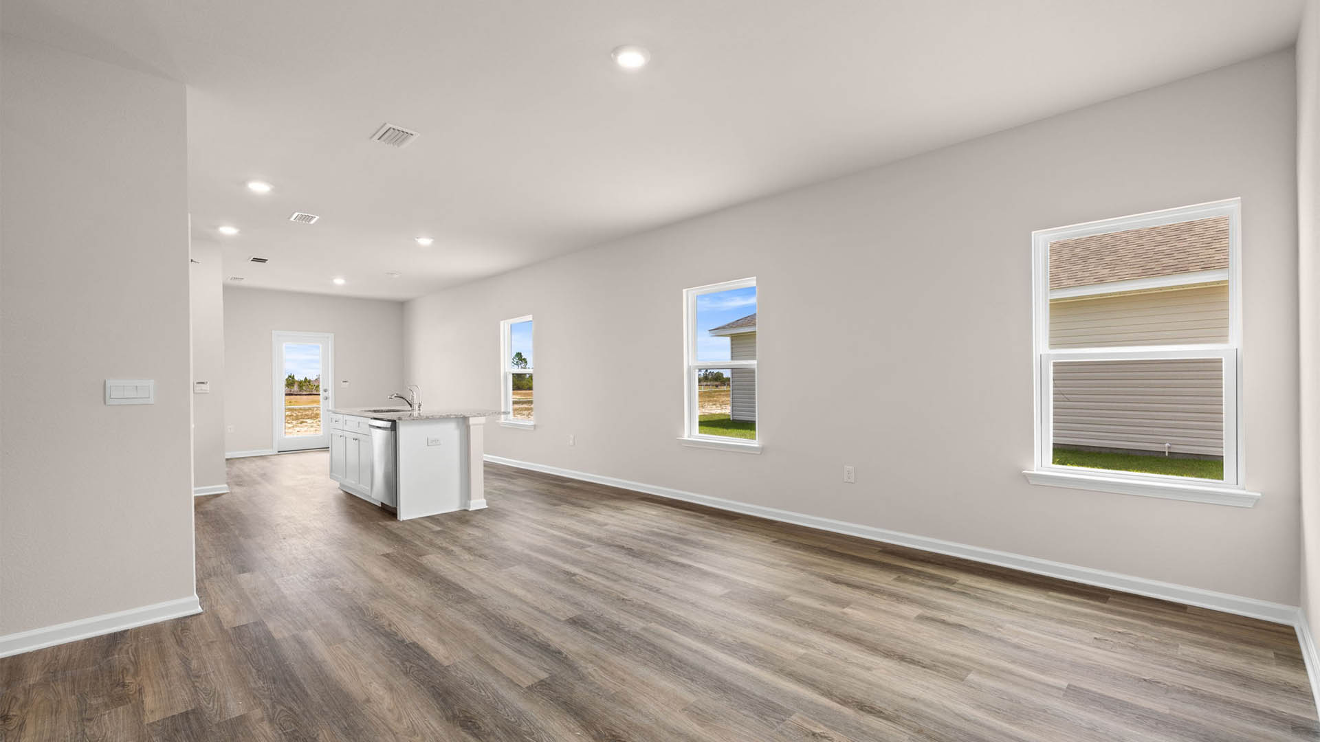 Open living room and kitchen with EVP flooring and windows.