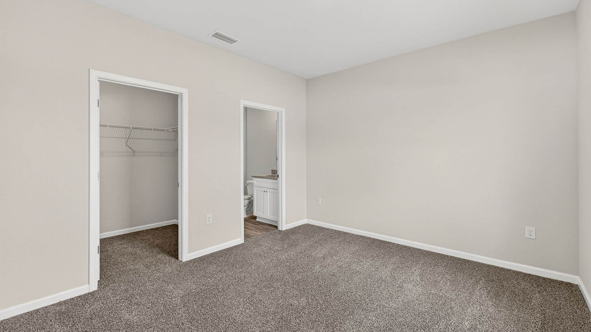Primary bedroom with carpet floor and closet and bathroom entrance.