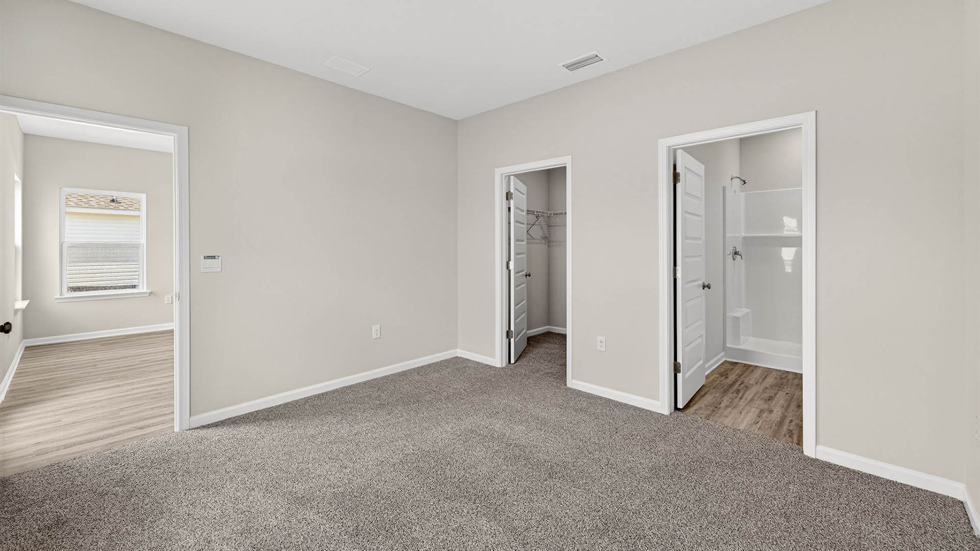 Primary bedroom with carpet floor and closet and bathroom entrance.