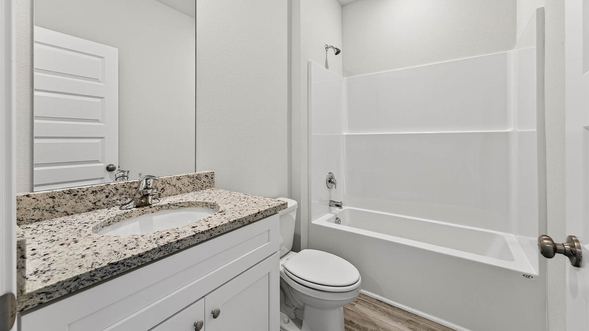 Bathroom with granite countertops and white cabinets and single vanity sinks and toilet and shower.
