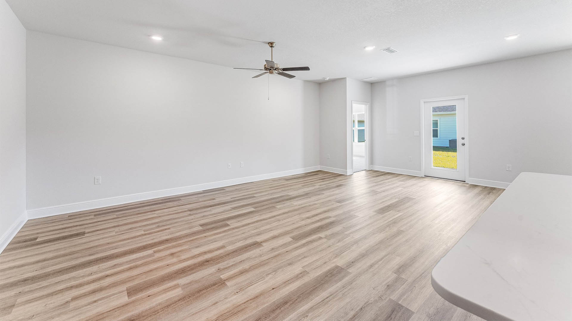 Open Living room with EVP flooring and ceiling fan and back door.
