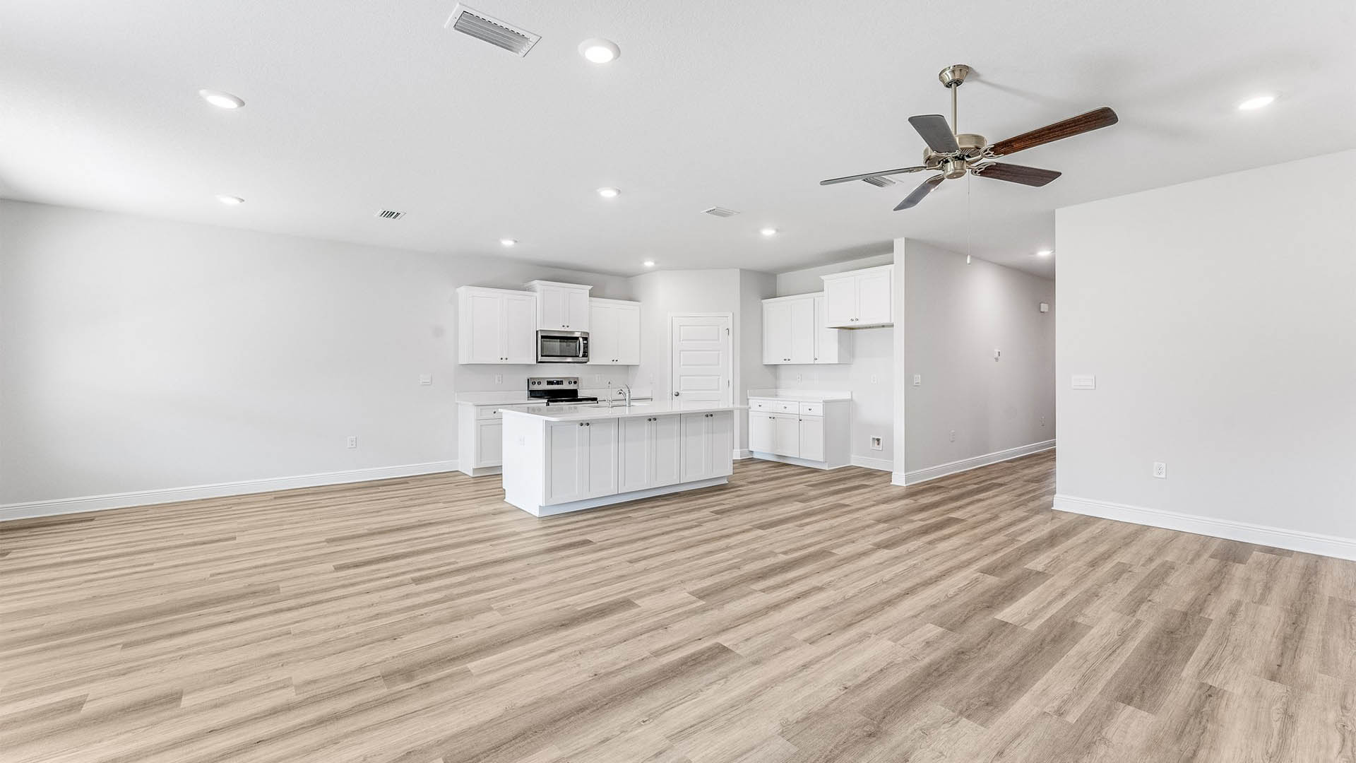 Open Living room with EVP flooring and ceiling fan and kitchen island with quartz countertops.