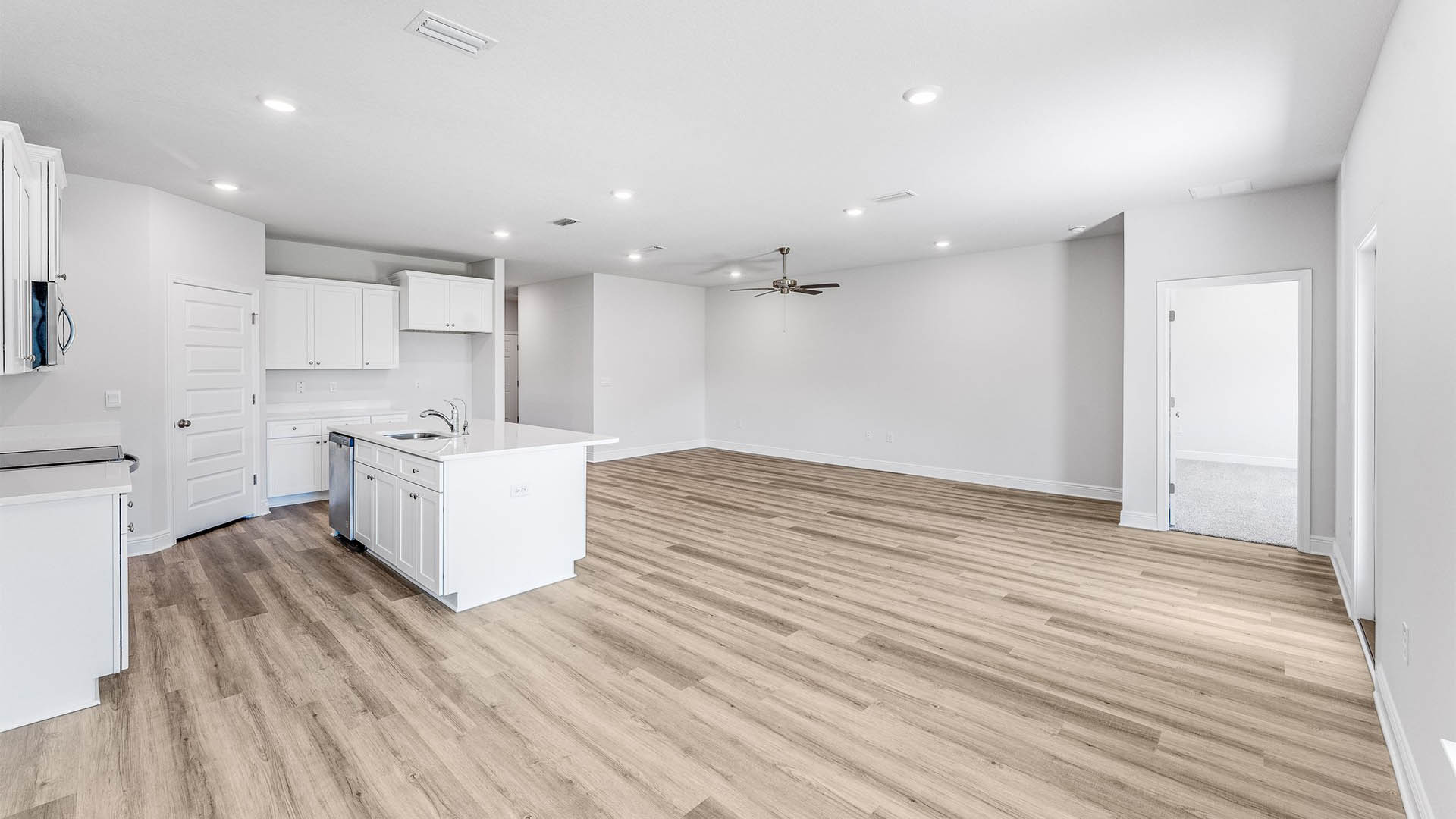 Open Living room with EVP flooring and ceiling fan and kitchen island with quartz countertops.