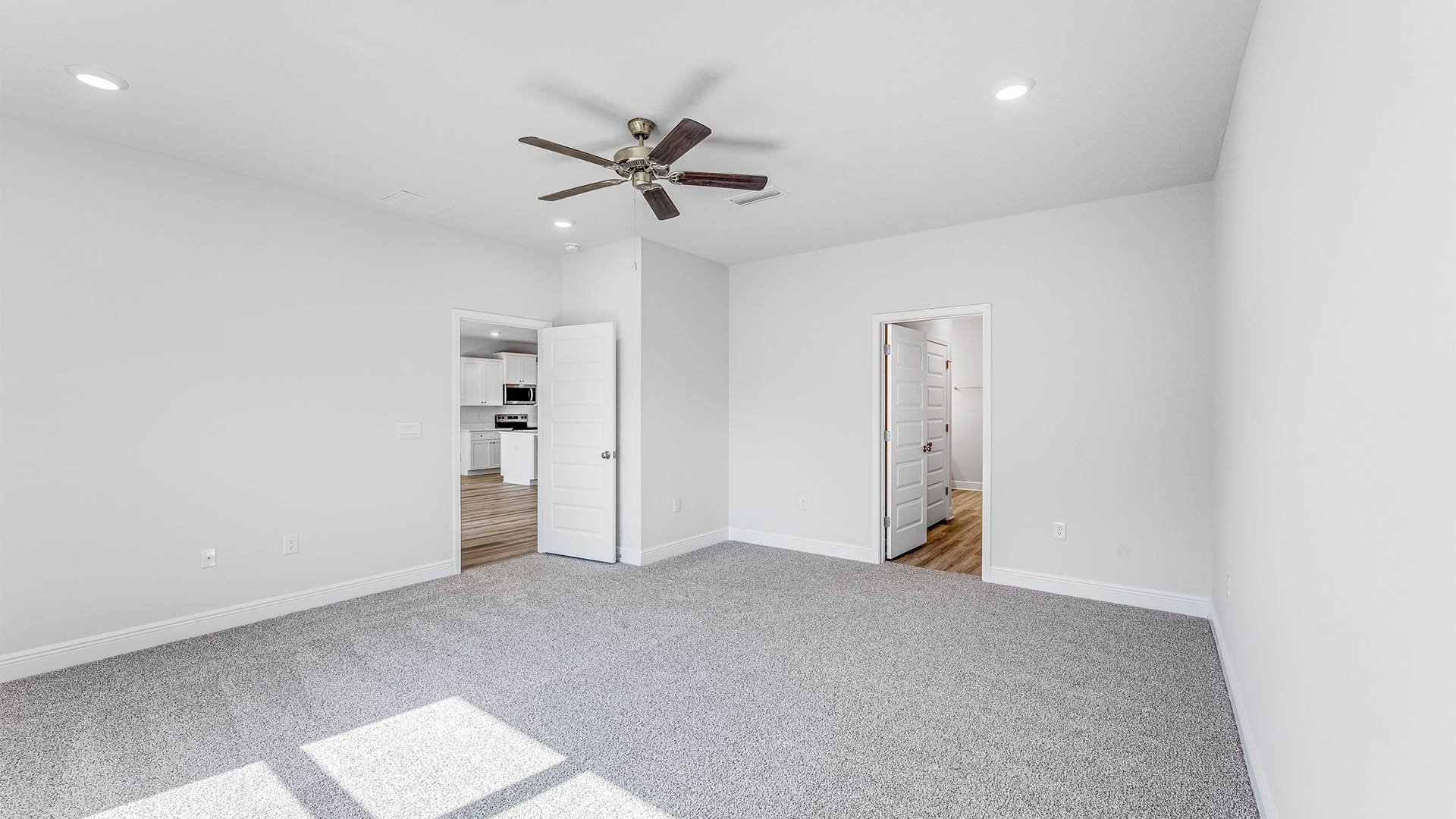 Primary bedroom with carpet floors and ceiling fan and bathroom.