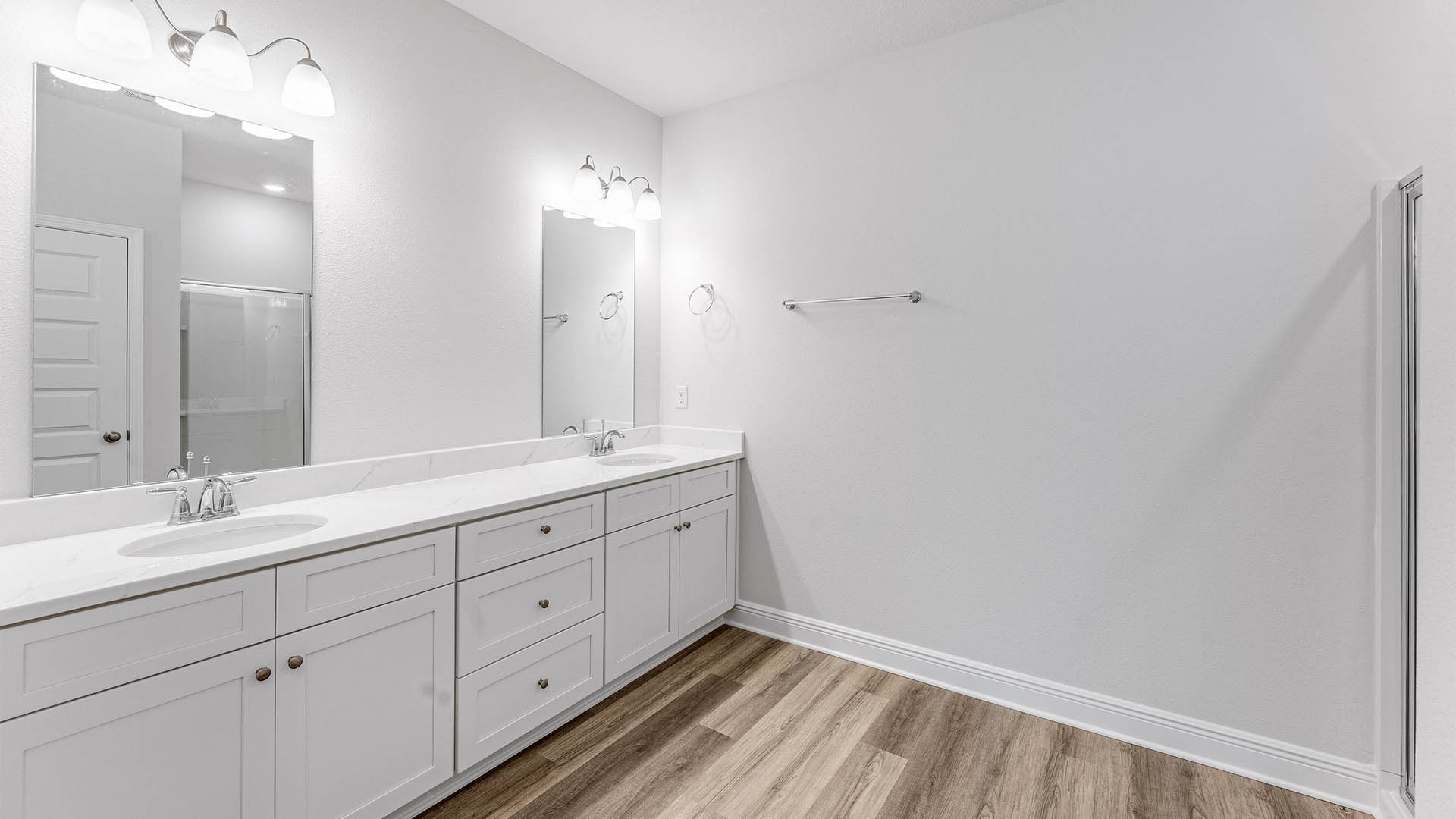 Primary bathroom with EVP flooring with white cabinets and quartz countertops and double vanity.