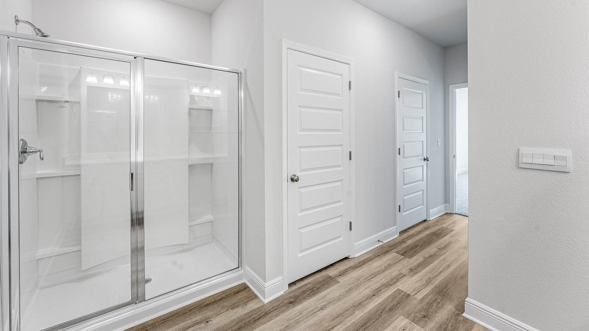 Primary bathroom with EVP flooring and shower with glass door and walk-in closet.