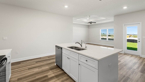 Kitchen with island and quartz countertops and white cabinets and stainless-steel appliances.